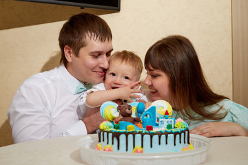 Obraz na płótnie Canvas Family with baby and cake for one year birthday in the room. Mom, dad and son together