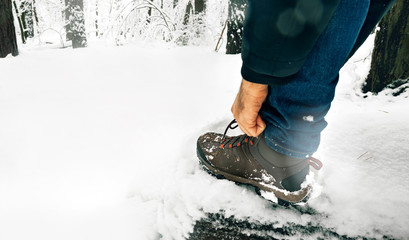 Man tying shoelaces boots winter snowy forest Lifestyle