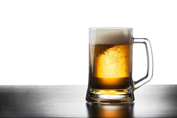 Frosty mug of light beer on black table