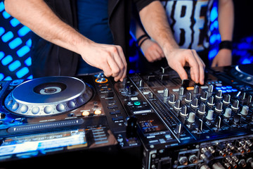 Naklejka premium Club party dj plays live set on stage in nightclub.Professional disc jockey mix popular musical tracks with vintage turnables & vinyl records