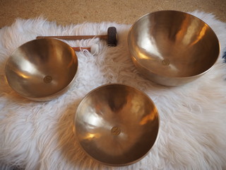 Three singing bowls in a row on a sheepskin for soundhealing, meditation and therapy.