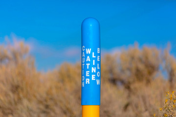 Water Line Below sign on a blue pole yellow base