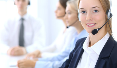 Call center. Group of operators at work. Focus at brunette business woman in headset