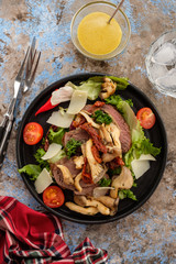 Salad with warm beef with oyster mushrooms, tomatoes and greens. Top view