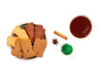 Spekulatius, traditional German Christmas cookies, shot from the top on a white background with hot chocolate, spices, a little Christmas tree, and copy space