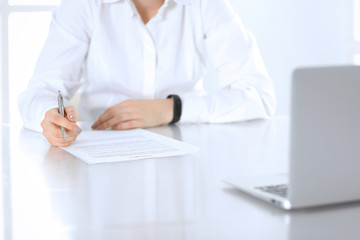 Fototapeta premium Close-up of female hands with pen over document, business concept. Lawyer or business woman at work in office