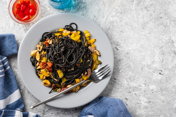 Black pasta with seafood, anchovies, tomatoes and bell peppers.