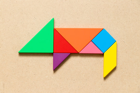 Color tangram puzzle in pig or hog shape on wood background