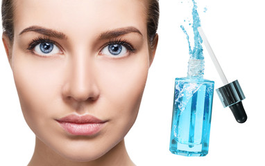 Beautiful face of young woman near blue cosmetic bottle.