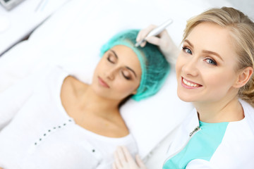 Professional beautician doing eyebrow tattoo at woman face. Permanent brow makeup in beauty salon, closeup.  Cosmetology treatment