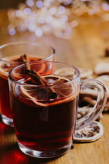 Mulled wine in mugs with scarf on wooden table.