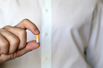 Doctor holding pill, male hand with medication in capsule close-up. Man with tablet, concept of pharmacist, drugs, diet pill, antibiotics or vitamins