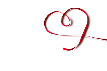 Isolated red satin ribbon with shape heart on white background. Concept of love, celebration, care, health, life.