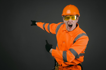 Angry and annoyed builder worker or architect is showing on a copy space behind him and is shouting about bad done work. A foreman discontented by a work.