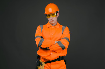 Serious builder construction worker standing with crossed arms isolated on gray background with...