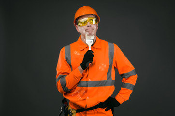 Confused painter worker with dirty face in a paint is standing and looking on the wall and is...