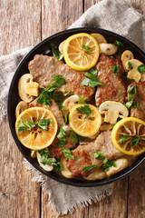Italian main course veal scaloppini cooked with mushrooms and lemons in a spicy sauce, close-up....