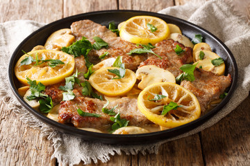 Scaloppini tender veal cooked with mushrooms and lemons in a spicy sauce close-up in a frying pan on the table. horizontal