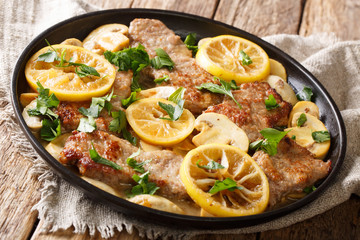 Italian recipe of delicious veal scaloppini cooked with mushrooms and lemons in a spicy sauce, close-up in a pan. horizontal