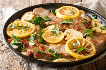 Italian main course veal scaloppini cooked with mushrooms and lemons in a spicy sauce, close-up....