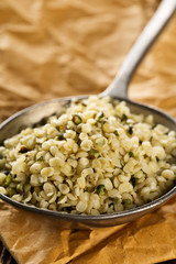 Heap of raw, organic hemp seeds in metal scoop on brown paper
