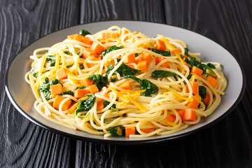 Simple vegetarian spaghetti recipe with pumpkin, spinach and cheese closeup on a plate. horizontal