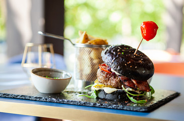 Black burger crafted by chef with french fries in restaurant