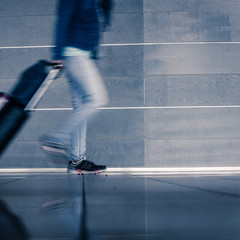 Fototapeta premium Closeup of traveler male legs walking and carrying baggage in train station