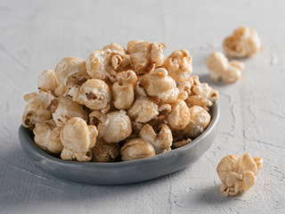 popcorn in gray craft trendy plate on gray concrete background. Moovie background with copy space. Top view or flat lay.