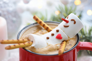 Red mug with cappuccino with melted marshmallow snowman