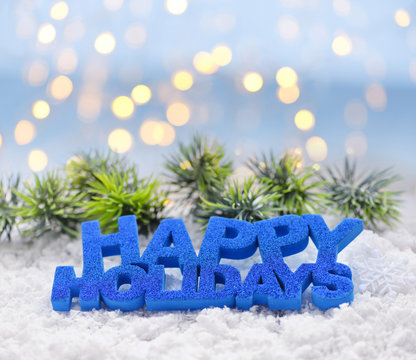 Greeting "Happy Holidays" on snow against the background of festive lights. Christmas or New Year greeting card.