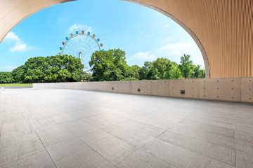 Empty square floor and ferris wheel in green city park