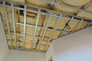 A metal frame of a ceiling under construction insulated with mineral wool 
