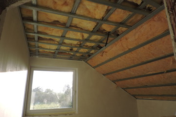 A room with a metal frame of a ceiling under construction insulated with mineral wool 