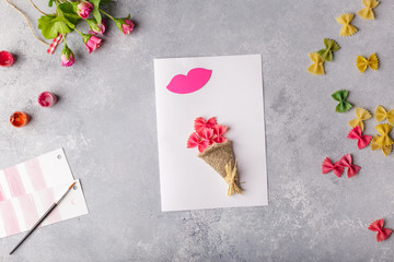 Paper crafts for mother day, 8 march or birthday. Small child doing a bouquet of flowers out of colored paper and colored pasta for mom. Simple gift idea. view top, copy space
