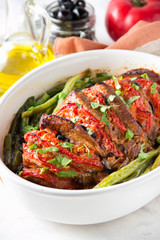 Baked whole pork meat with tomatoes, green beans and black olives, homemade cozy winter dish in a pot. Christmas tasty food