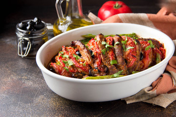 Baked whole pork meat with tomatoes, green beans and black olives, homemade cozy winter dish in a pot. Christmas tasty food