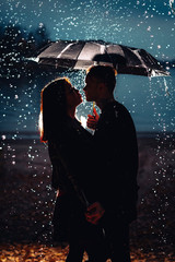 young man and woman under an umbrella and rain
