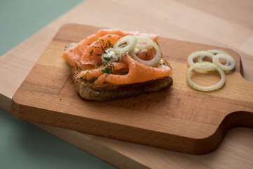 Geräucherter Lachs auf Vollkorn Toast Brot mit Zwiebeln, Dill und Meerrettich auf Holz Brett
