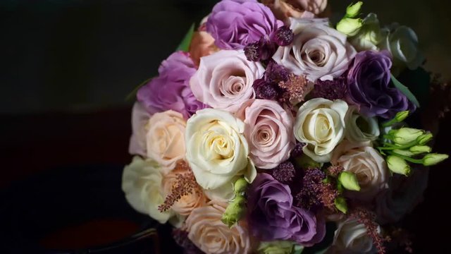 close-up, beautiful wedding bouquet of roses dairy, white and lilac. in the darkness. playing of light and shadows.