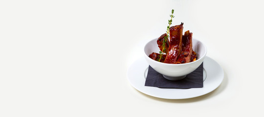 BBQ Ribs in a white bowl on a white plate on a white background isolated