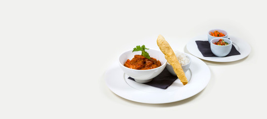 Indian Curry in a white bowl with rice on a white plate on a white background isolated