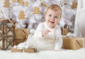 Little girl sitting under a Christmas tree with gifts