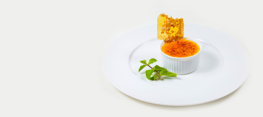 creme brulee and caramel flake on a white plate on a white background isolated
