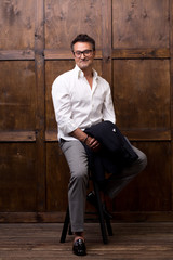 Confident middle aged man holding his jacket while sitting on the bar stool