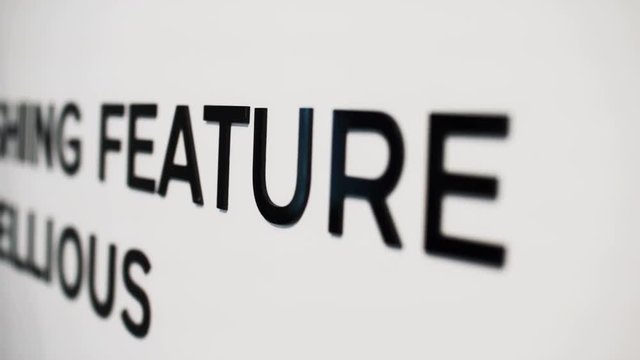 Camera is slowly showing big printed words by revealing black colour letter by letter on brigt white background.