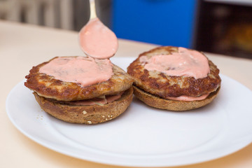 Preparing delicious burgers. Chef cooking meat burgers with bacon, cheese and vegetables, selective focus. Close-up.