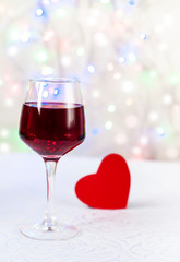 glass of red wine and a red heart on a white background, Valentine's Day