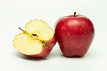 one whole red apple and half an apple next to it on a white background