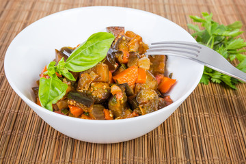 Braised chopped eggplants with other vegetables in bowl close-up